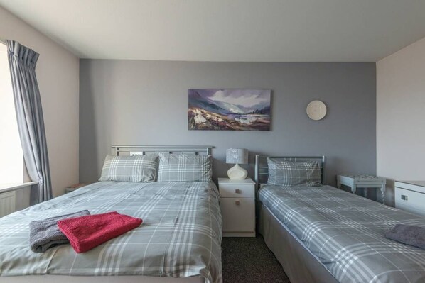 A hotel room with two beds, a painting on the wall, and a bedside table with a lamp.