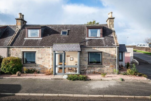 A stone house with a small front porch, two windows, and a door. - Highland 'Home from Home' with panoramic view of Cromarty Firth (Invergordon)