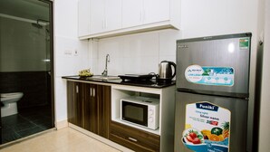 A modern kitchen with a microwave, kettle, and a refrigerator with a promotional sticker. - KorHan Apartment (Hanoi)