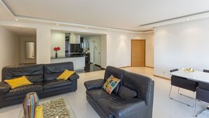 A modern living room with two leather sofas, a coffee table, and a dining area with a table and chairs. - 3 BEDROOM APARTMENT IN THE CENTER OLHAO (Olhão)