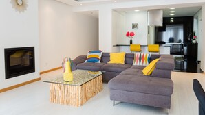 A modern living room with a sectional sofa, a glass coffee table, and a fireplace. - 3 BEDROOM APARTMENT IN THE CENTER OLHAO (Olhão)