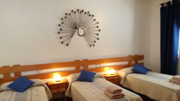 Une chambre d’hôtel avec deux lits, chacun doté d’une tête de lit en bois, d’une table de chevet avec une lampe et d’un élément décoratif mural.