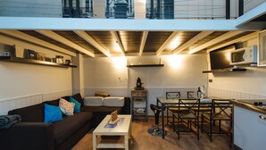 A compact living space with a sofa, a small table, a kitchen area with a microwave, and a dining table with chairs.