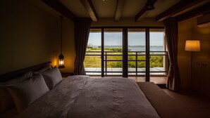 Una habitación de hotel con una cama grande, vistas al mar y un balcón.