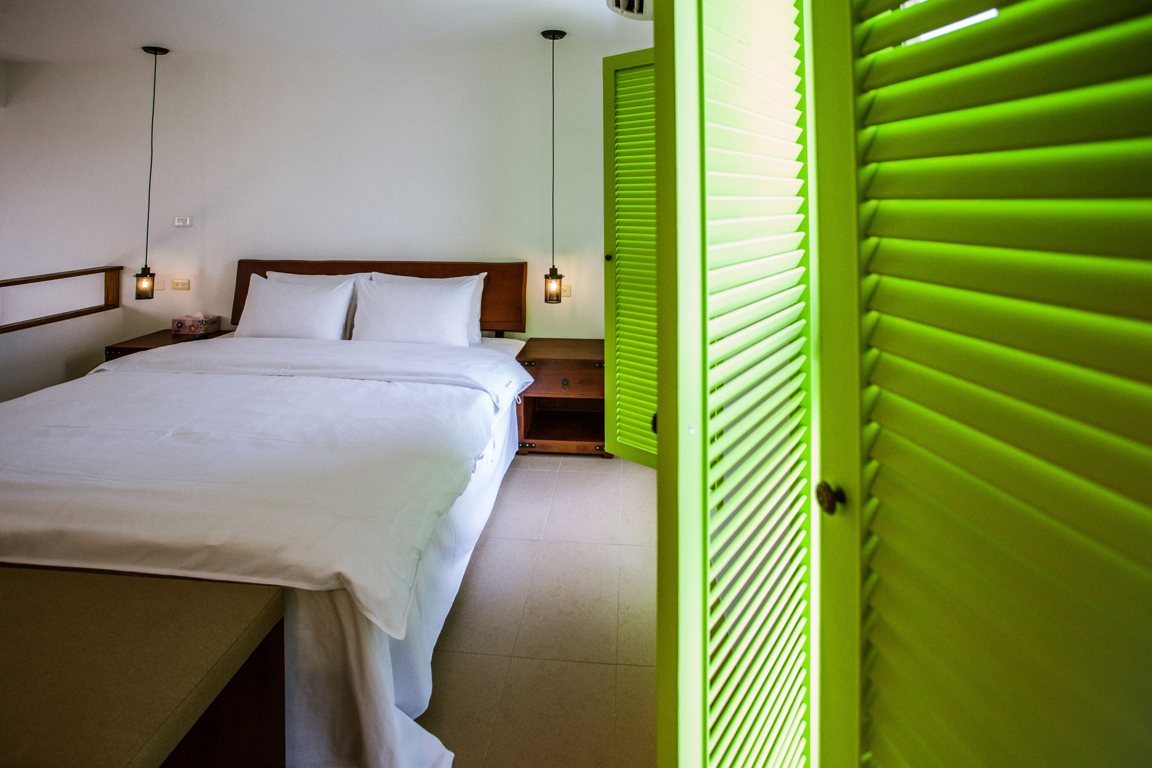 A neatly made bed with white linens, a wooden headboard, and bedside lamps.