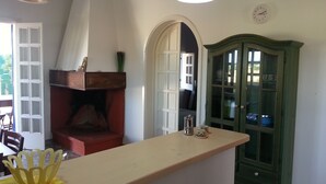 A kitchen with a wooden counter, a green cabinet, and a white wall clock.