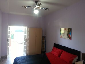Un dormitorio con una cama, un ventilador de techo, un armario y un cuadro en la pared.