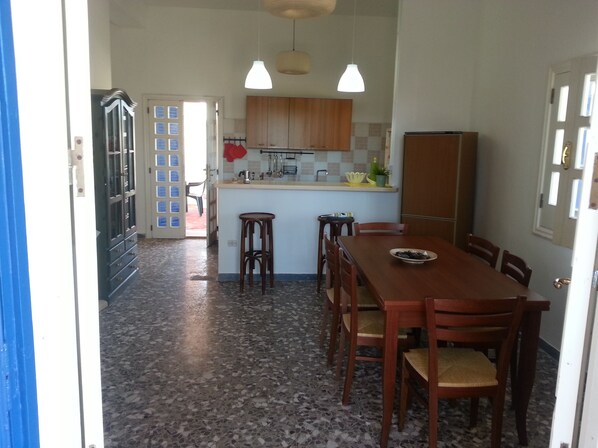 Una cocina con una mesa de comedor, sillas, un refrigerador y un lavamanos.