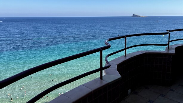 A balcony with a view of the ocean and a distant ship.