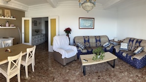 A living room with a dining table, chairs, a sofa, and a coffee table.