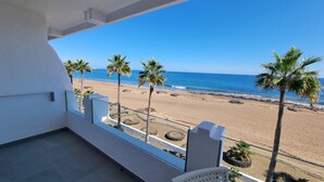 Un balcón con vistas a una playa, palmeras y el océano.