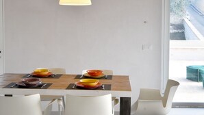 A modern dining area with a wooden table, white chairs, and a hanging lamp. - For those who love to pause in history and stories (Assisi)