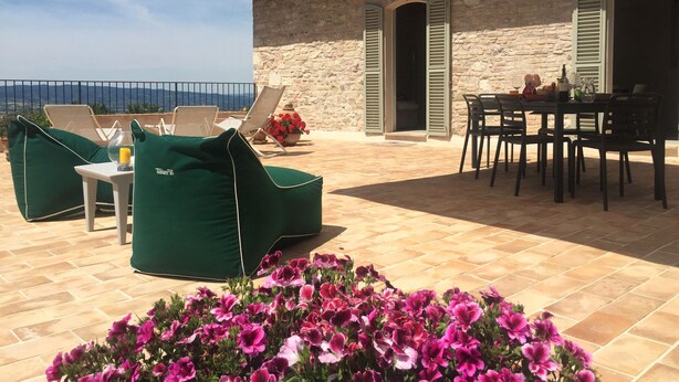 A terrace with stone walls, outdoor furniture, and a view of the sea. - For those who love to pause in history and stories (Assisi)
