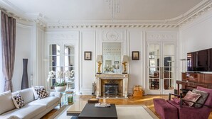 Ein geräumiges Wohnzimmer mit Kamin, Sofa, Couchtisch und einem violetten Sessel.