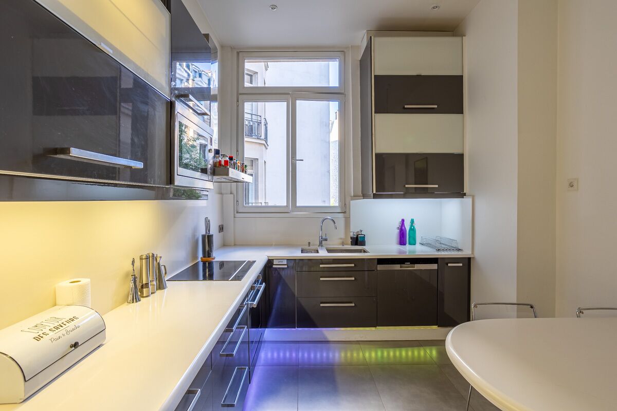 A modern kitchen with a built-in oven, a sink, and a window providing natural light.