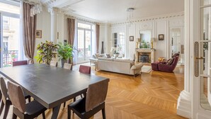 Ein geräumiges Wohnzimmer mit großem Esstisch aus Holz, bequemen Sitzmöglichkeiten und einem Kamin.