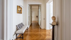 Ein Korridor mit einer Bank, einem Büstenstamm auf einem Sockel und einem gerahmten Bild an der Wand.
