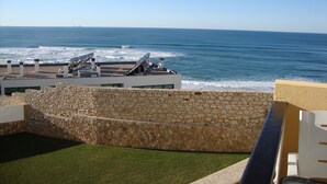 A rooftop terrace with a view of the ocean, stone walls, and a grassy area. - Apartment with open views to the Atlantic Ocean (Foz do Arelho)