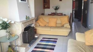 A living room with a beige sofa, a fireplace, a striped rug, and a small table with decorative items. - Apartment with open views to the Atlantic Ocean (Foz do Arelho)