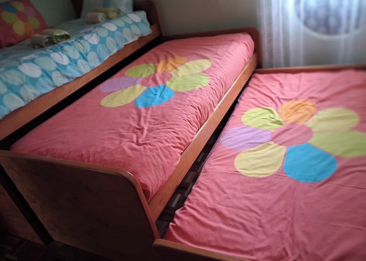 Ein Bett mit einer rosa Bettdecke und einem Kissen mit blauen und weißen Punkten.