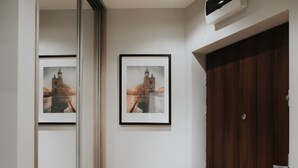 A hallway with wooden flooring, a large mirror, and two framed pictures on the wall. - Mia Apartments (Kraków)