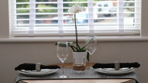Una mesa de comedor dispuesta con platos, vasos y un jarrón con una orquídea.