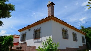 A two-story building with a tiled roof, a chimney, and barred windows. - House with barbecue and fireplace, ideal for summer and winter. (Bolonia)