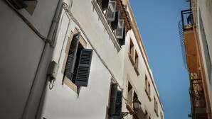 A building with multiple windows, some with shutters, and a clear blue sky in the background.