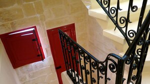 A staircase with a black wrought iron railing and red doors.