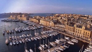 A marina with numerous boats docked, surrounded by a densely packed urban area with historic buildings.