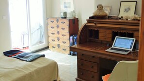 A bedroom with a bed, a desk with a laptop, a dresser, and a chair.