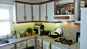 A kitchen with white cabinets, a gas stove, a coffee maker, and various kitchen utensils.