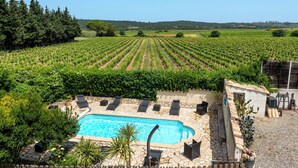 A swimming pool surrounded by lounge chairs and a vineyard in the background. - Character gite with swimming pool, surrounded by vineyards, 30 min drive from the Mediterranean coast. (Fabrezan)