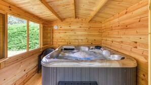 A wooden cabin with a hot tub, large windows, and a view of greenery. - Character gite with swimming pool, surrounded by vineyards, 30 min drive from the Mediterranean coast. (Fabrezan)