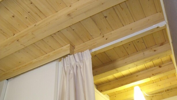 Una habitación con techo de madera, pared blanca y una lámpara colgante.