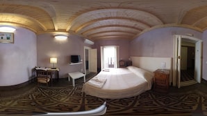 Una habitación con una cama, un escritorio, una silla, un televisor y una puerta que da a otra habitación.