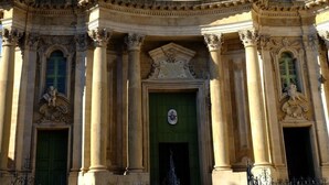 Un edificio histórico con arquitectura ornamentada, que presenta columnas, estatuas y una entrada destacada.