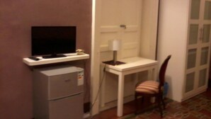 Una habitación pequeña con un escritorio, una silla, un televisor y un archivador.