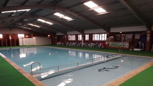 An indoor swimming pool with a tiled edge, surrounded by artificial turf and a wooden deck. - 5* Light & Airy Chalet 5min walk 2 beach nr BroadsSunbeach Chalets 143 a contemp (Great Yarmouth)