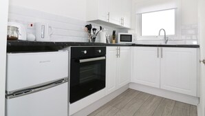 A modern kitchen with white cabinetry, a black oven, a microwave, and a window above the sink. - 5* Light & Airy Chalet 5min walk 2 beach nr BroadsSunbeach Chalets 143 a contemp (Great Yarmouth)