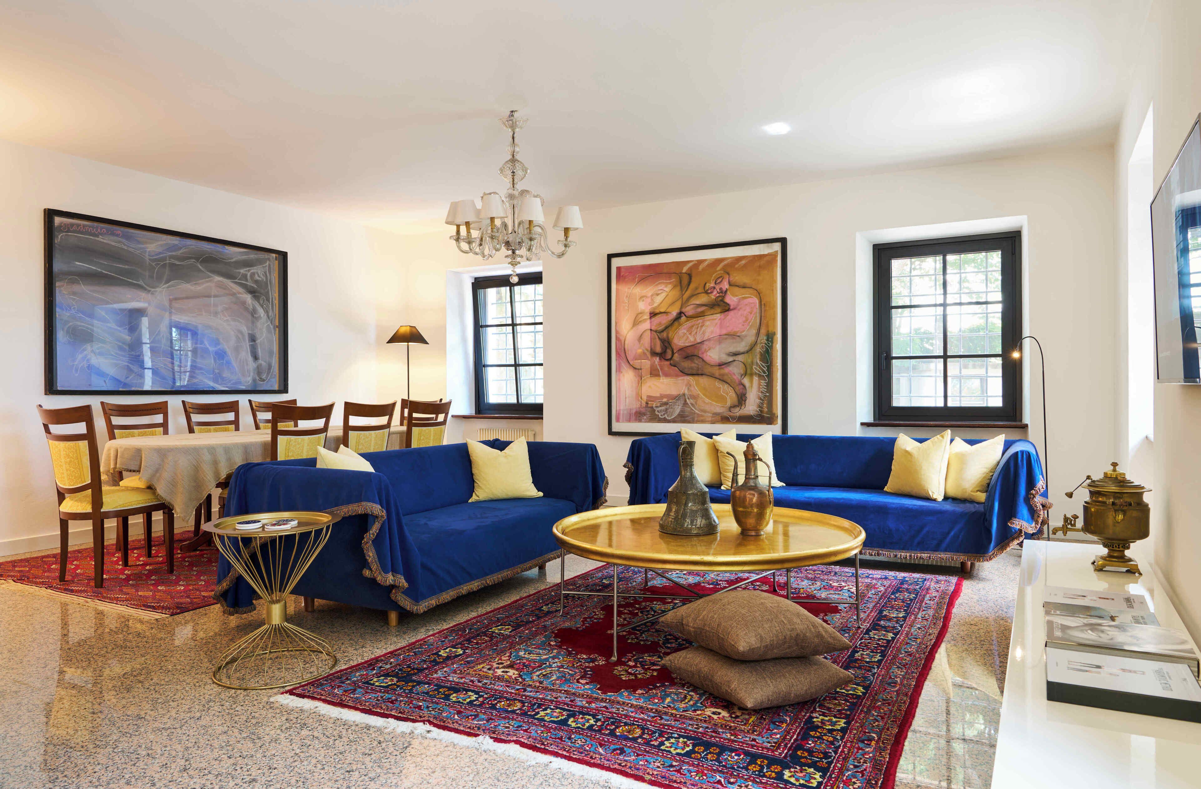 A living room with a blue sofa, a round coffee table, and a large rug.