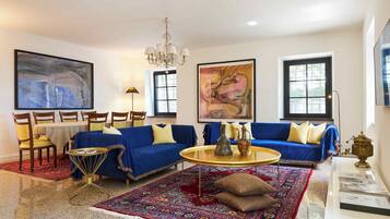 A living room with a blue sofa, a round coffee table, and a large rug.