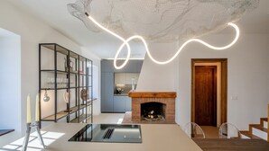 Une cuisine moderne dotée d’une cuisinière intégrée, d’une table à manger en bois et d’une cheminée.