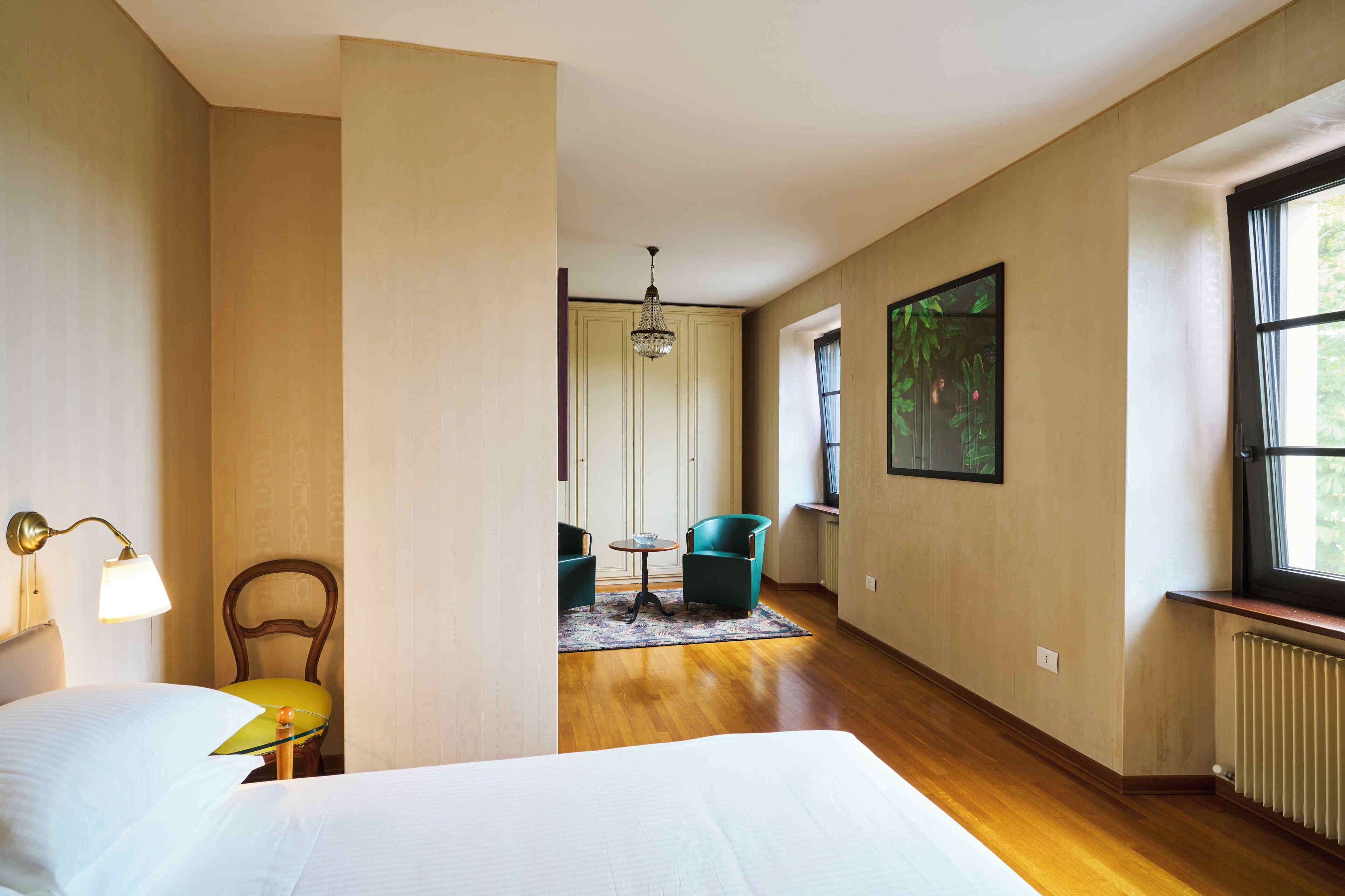 Een hotelkamer met een bed, een stoel, een tafel, een lamp en een raam.