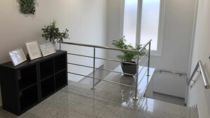 Um interior moderno com escada, balcão de recepção e uma janela ampla.