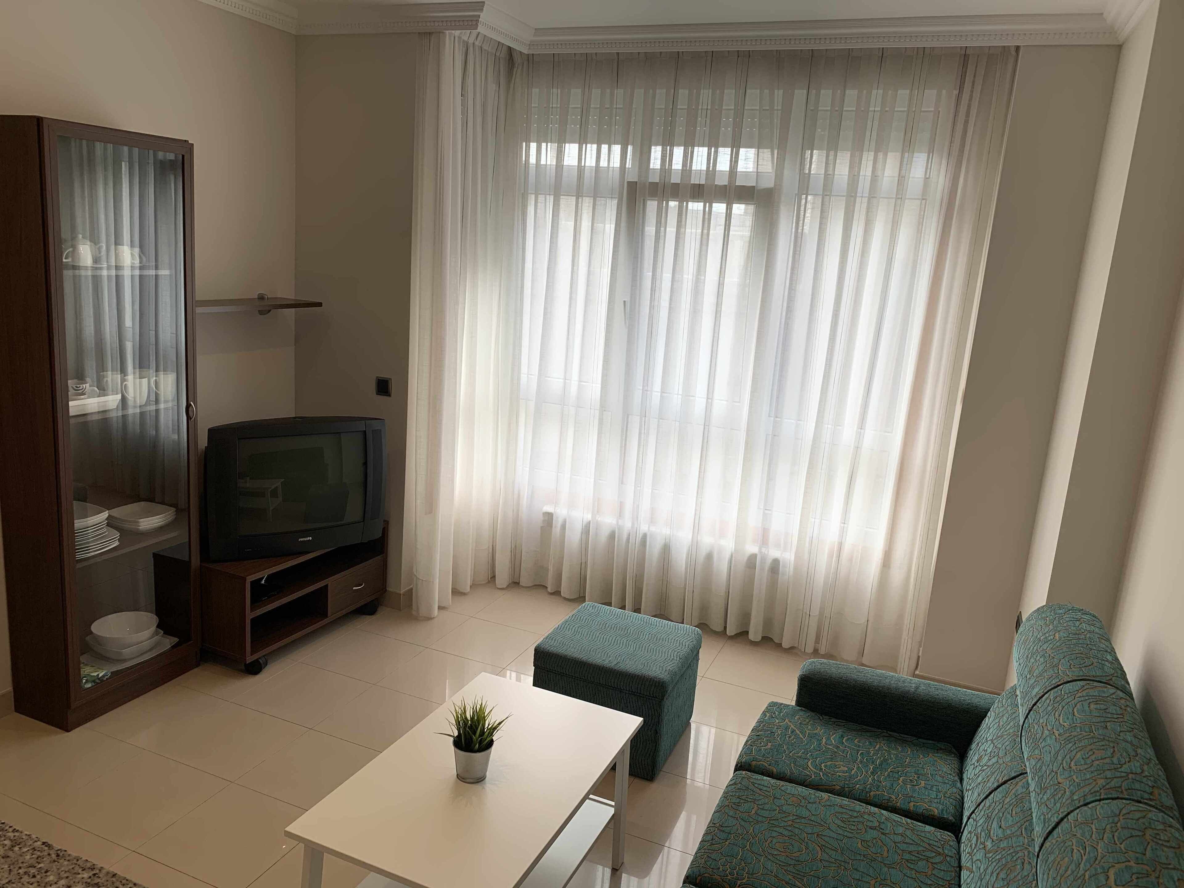 Una sala de estar con televisor, sofá, mesa de centro y aparador con vajilla.