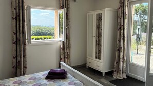 Un dormitorio con cama, armario y ventana con cortinas.