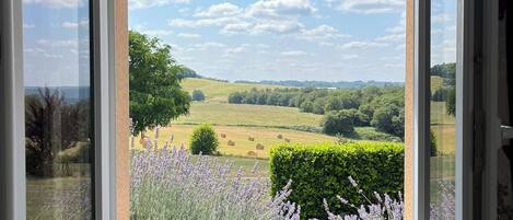 A room with a large window overlooking a countryside landscape.