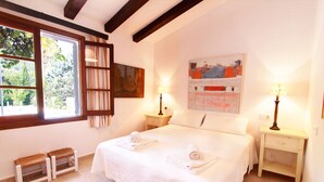 A bedroom with a large bed, two bedside tables, a window with curtains, and a painting on the wall. - Private Grounds, Walking Distance to Puerto Pollensa, New PS5, Bikes (Puerto Pollensa)