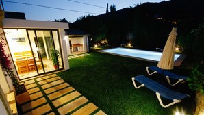 A modern house with a swimming pool, a patio with lounge chairs, and a well-lit interior. - Private Grounds, Walking Distance to Puerto Pollensa, New PS5, Bikes (Puerto Pollensa)